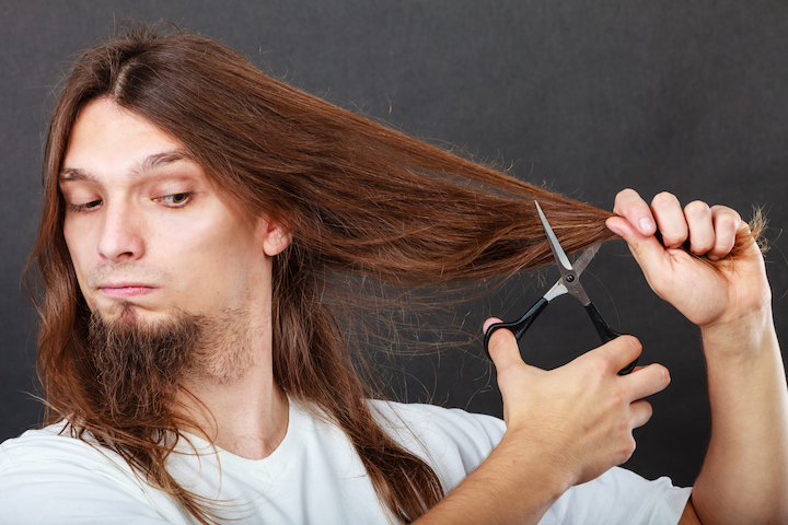 Man With a Long Hair and Extended Goatee Cutting Hair With Scissors