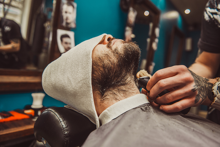 Man With a Towel on His Head Getting His Beard Trimmed By Barber