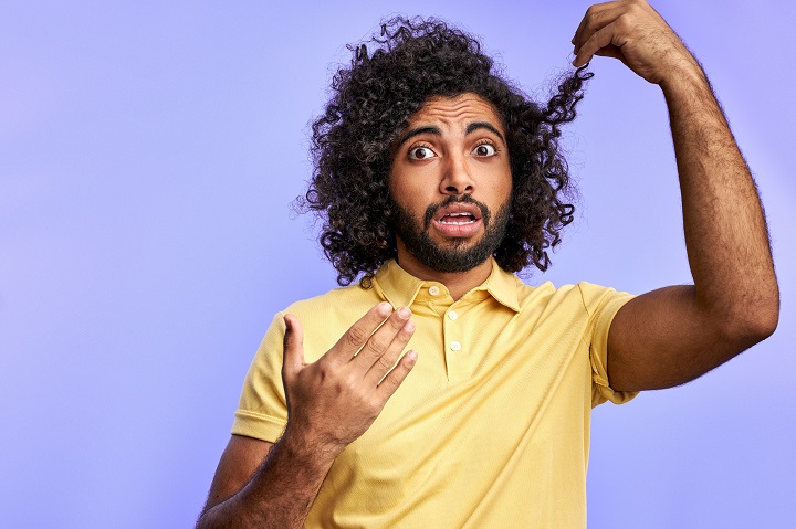 Man Looking Camera Holding Curly Hair Ends