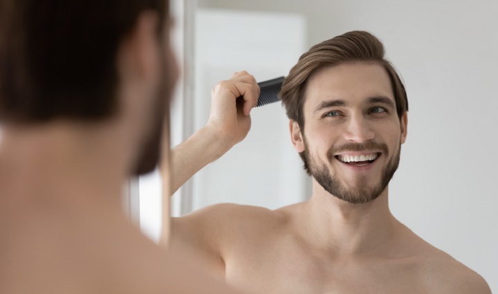 Young Man Combing His Hair and Smiling