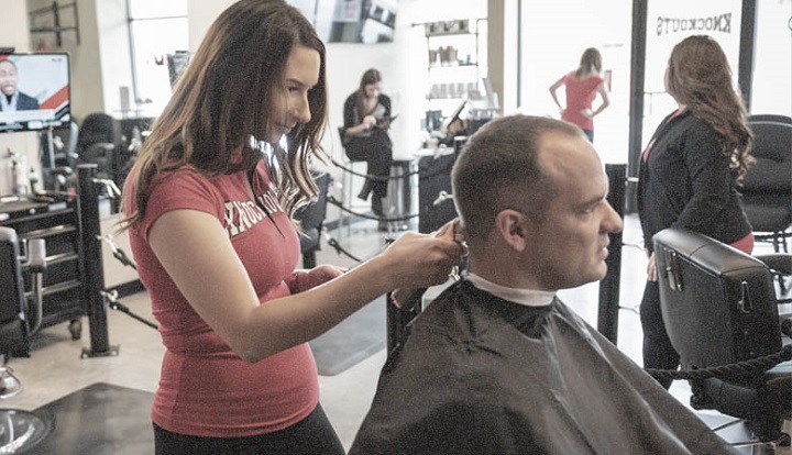 Female Barber Trimming Man's Hair in a Salon