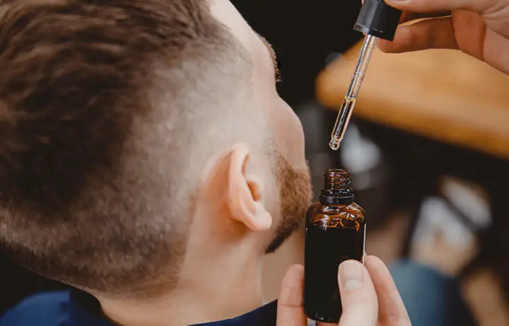 Barber Putting Oil on Men's Beard