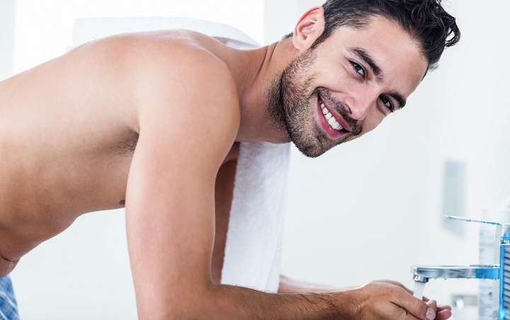 Smiling Young Man Washing His Beard