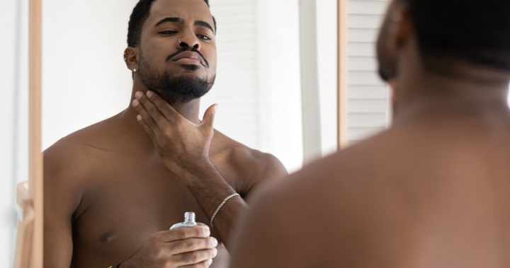 Black Man Applying After Shave Lotion On His Face