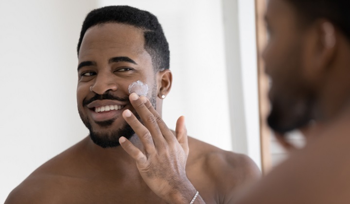 Black Man Applying Aftershave Balm On His Face