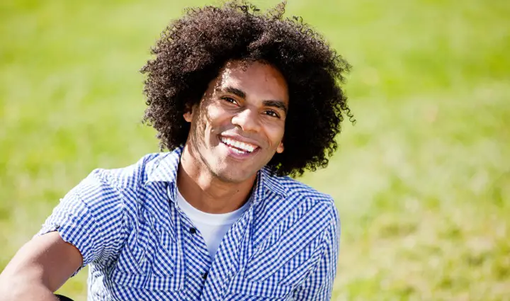 Smiling Black Man in a Blue Shirt With Curly Hair