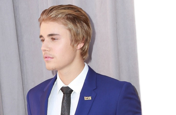 Justin Bieber With Slicked Back Blonde Hairstyle Wearing a Blue Suit