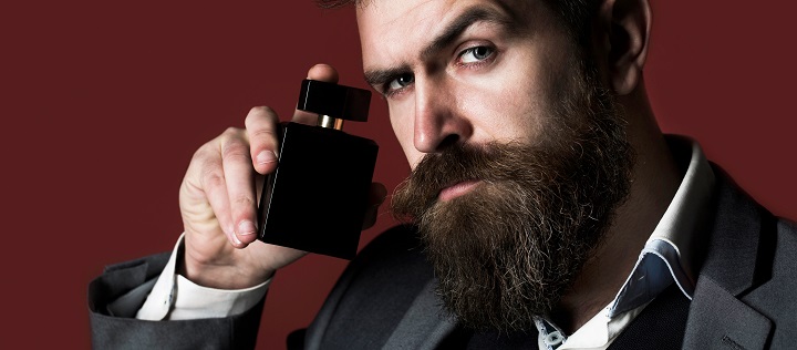 Bearded Man in a Suit Holding a Cologne Bottle