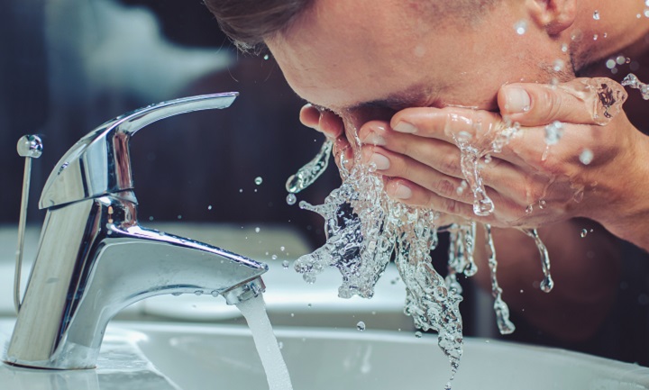 Man Washing His Face Over a Sink