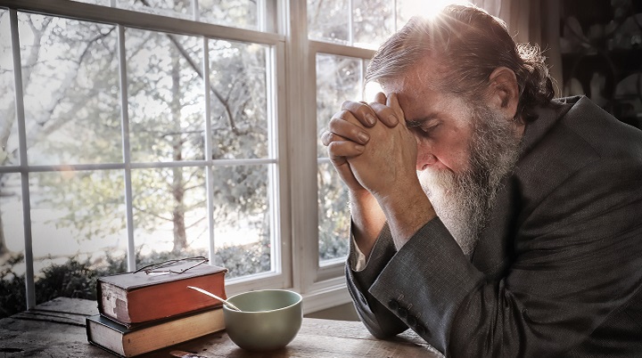 Man With Bible On Table And Beard Praying