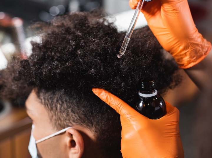 Applying Hair Oil to Black Man's Coarse Curly Hair