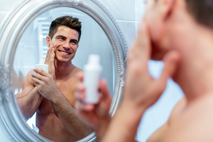 Man Applying an Aftershave Lotion in Front of the Mirror