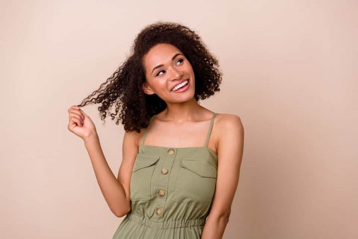 Smiling Girl Playing With Her Medium Length Curly Hair
