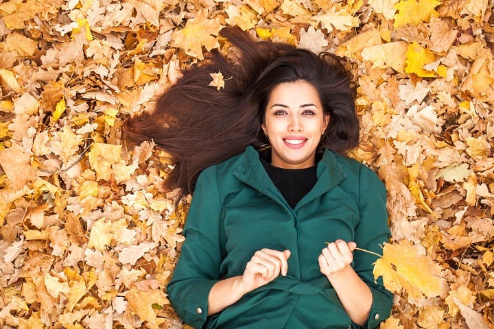Woman With a Chestnut Brown Hair in a Pale of Yellow Leaves