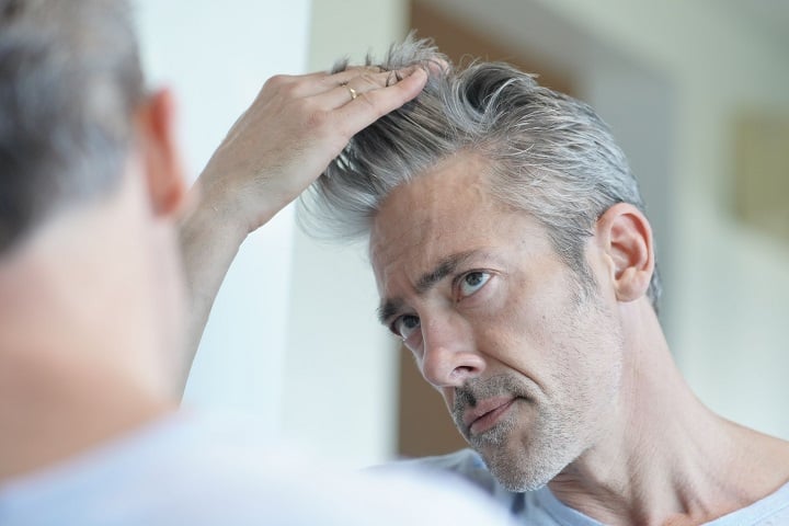 Greying Man Touching His Salt and Pepper Hair