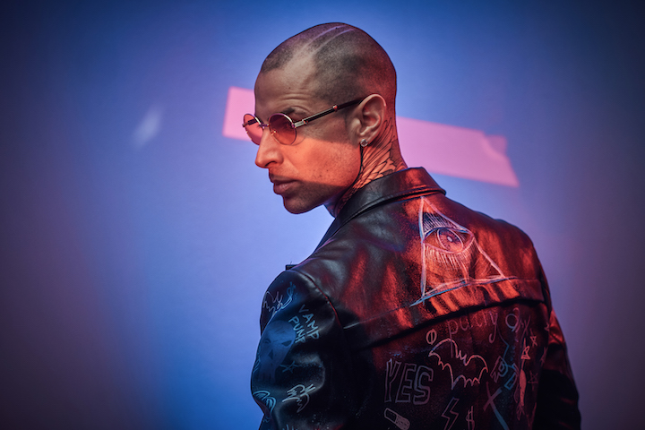 Tattooed Man in Rock Jacket Glasses and With Buzz Cut Hair
