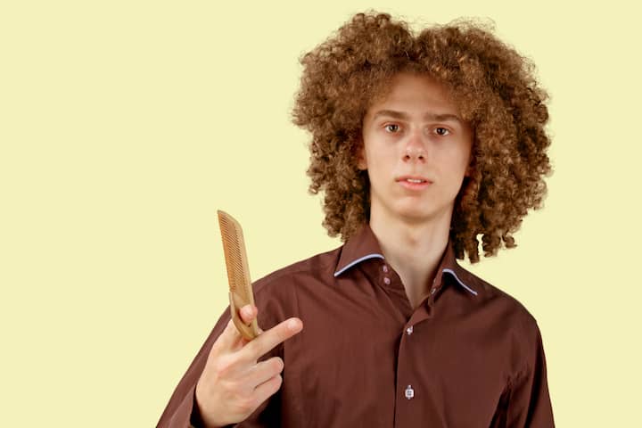 Long Haired Teenager With a Comb Over Haircut Holding a Comb